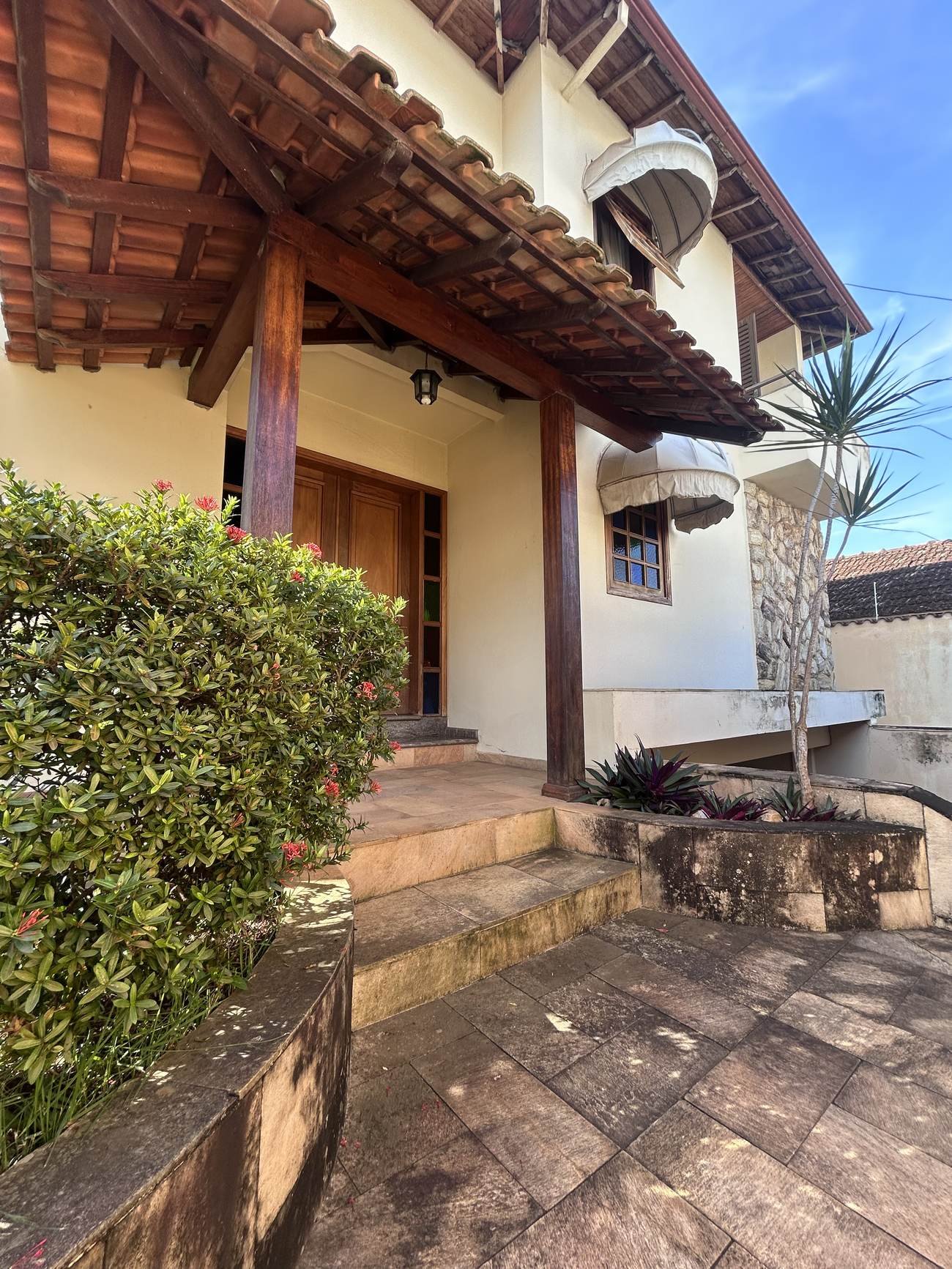 Fachada da residência em Varginha, com telhado colonial e jardim de entrada