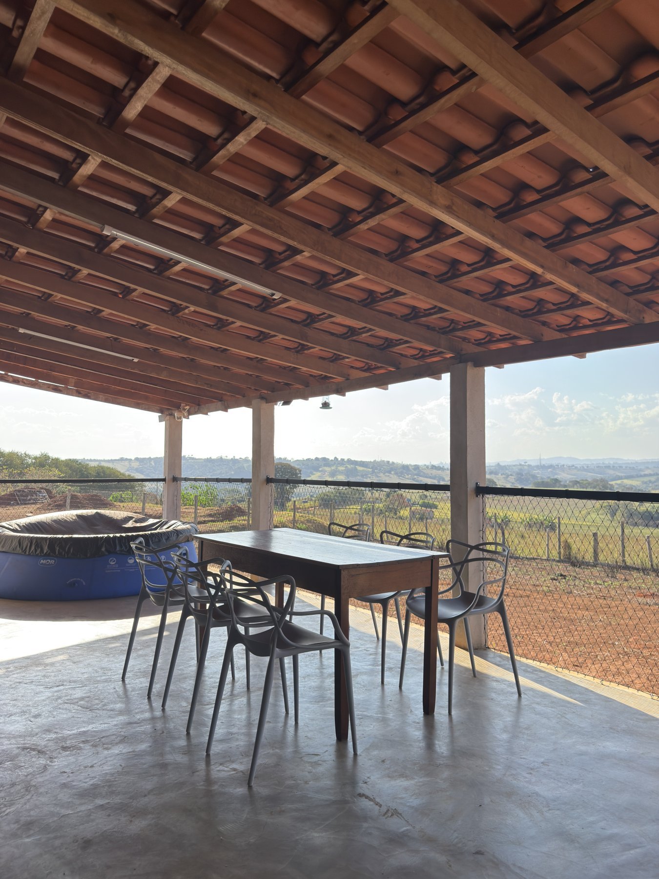 Varanda com mesa de jantar ao entardecer, vista para as colinas