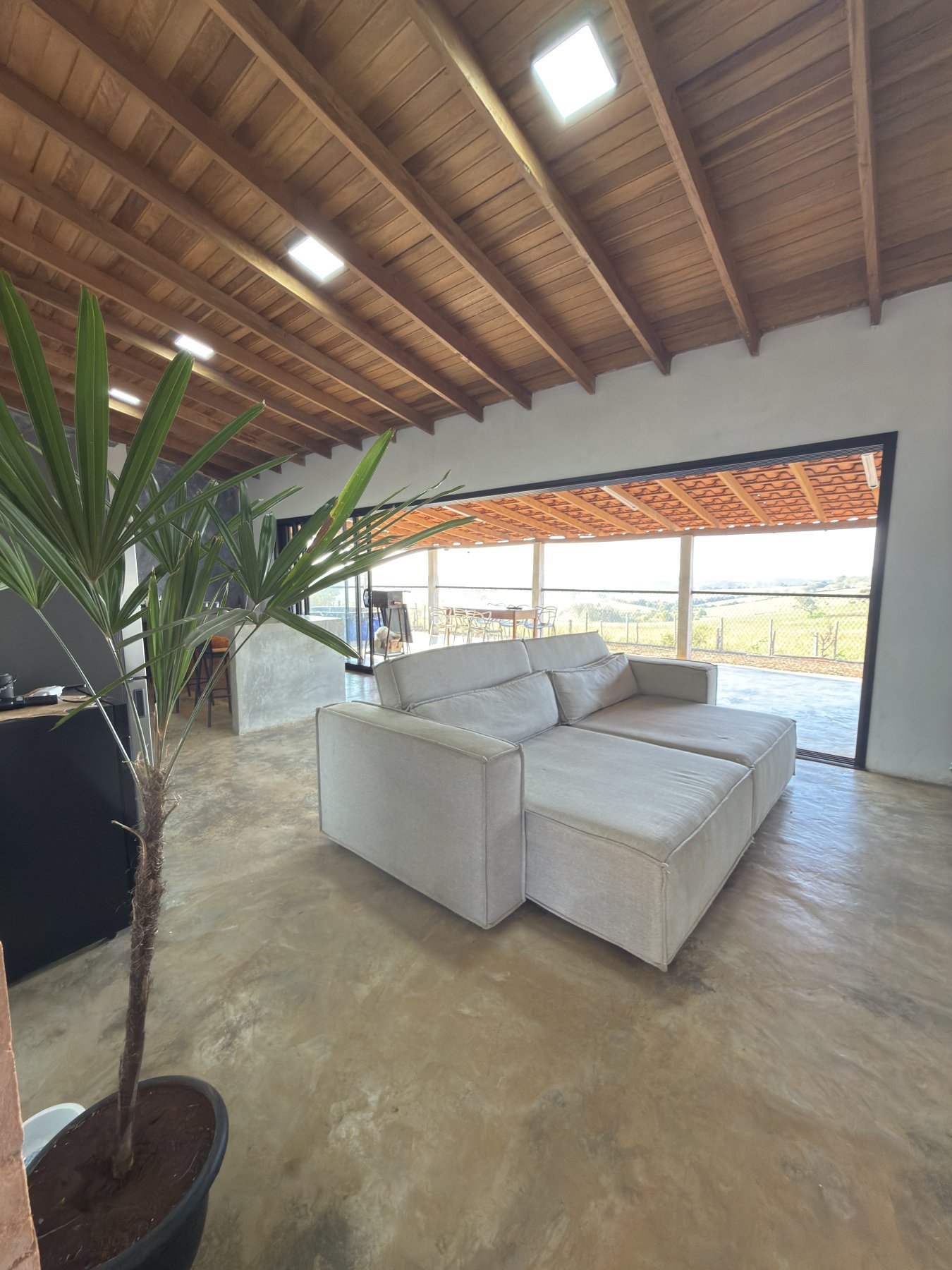 Sala de estar integrada, com porta de vidro para a varanda e vista para o campo